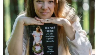 Žena drží knihu o vánočních věncích s jeřabinami v lese.