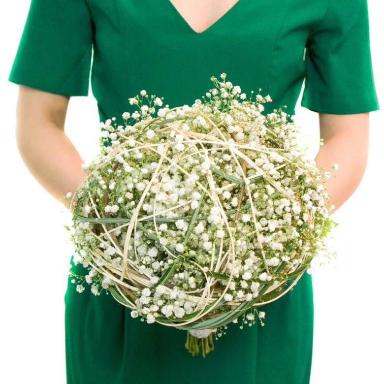 Květina gypsophila v kytici držená osobou ve zeleném šatu.