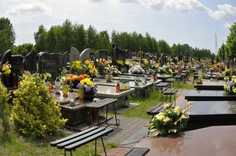 Hřbitov s barevnými trvalkami na hrobech pod modrou oblohou