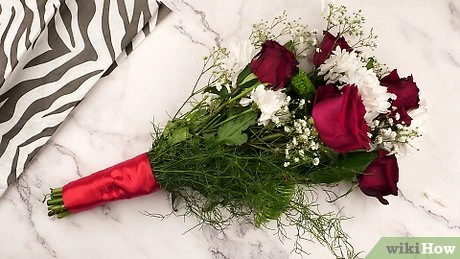 Kytice s červenými růžemi a zelenou výzdobou zabalit do červeno