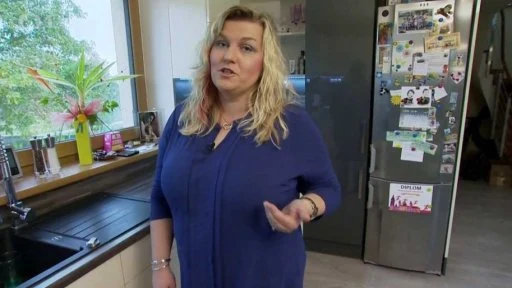 Žena v kuchyni s rostlinou selaginelou na okenním parapetu.