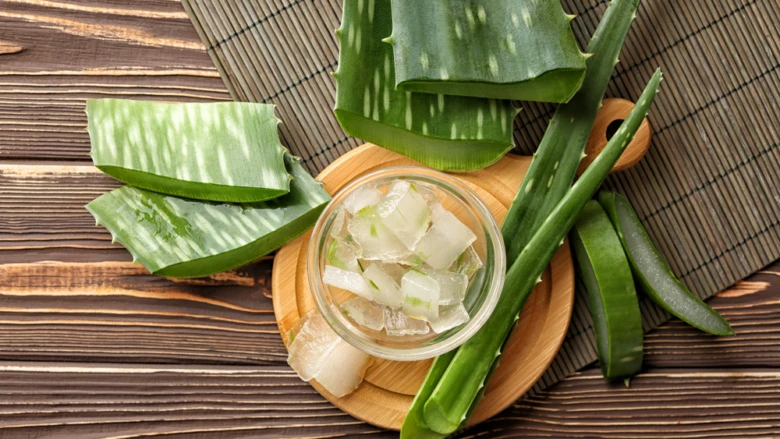 Čerstvé listy aloe vera s vybraným gelem na dřevěném podkladu.