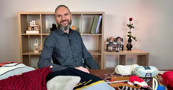 Muž sedící u stolu s pletacími materiály pro začátečníky.