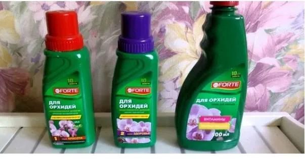 Tři lahve hnojiva pro orchideje značky Forte na polici.
