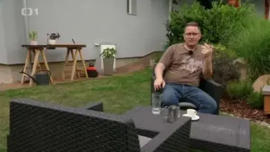 Muž sedí v zahradě mezi rostlinami s kalici.