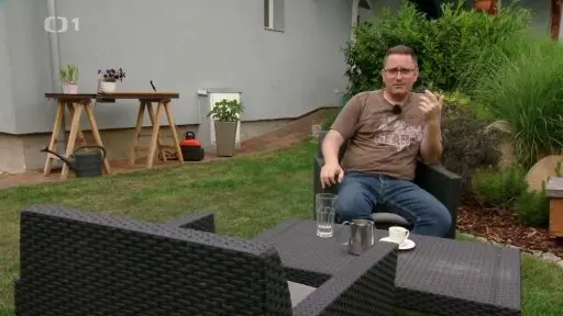 Muž sedí v zahradě mezi rostlinami s kalici.