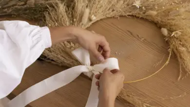 Ručník váže bílou stužku na věnec z suché trávy.